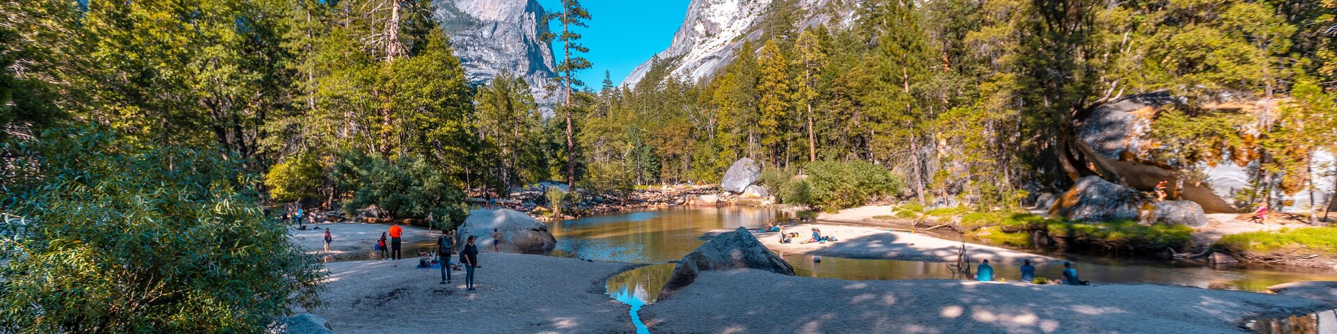 Un río de aguas cristalinas rodeado de terreno rocoso y un bosque denso.