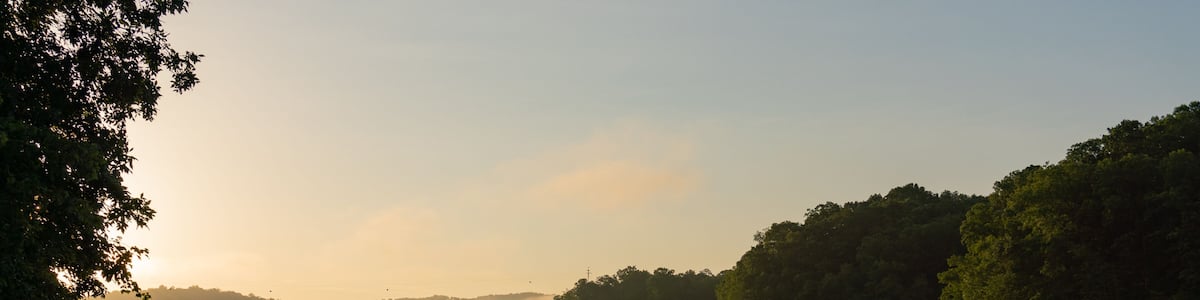 Un lac paisible, avec un quai et une colline boisée en arrière-plan.
