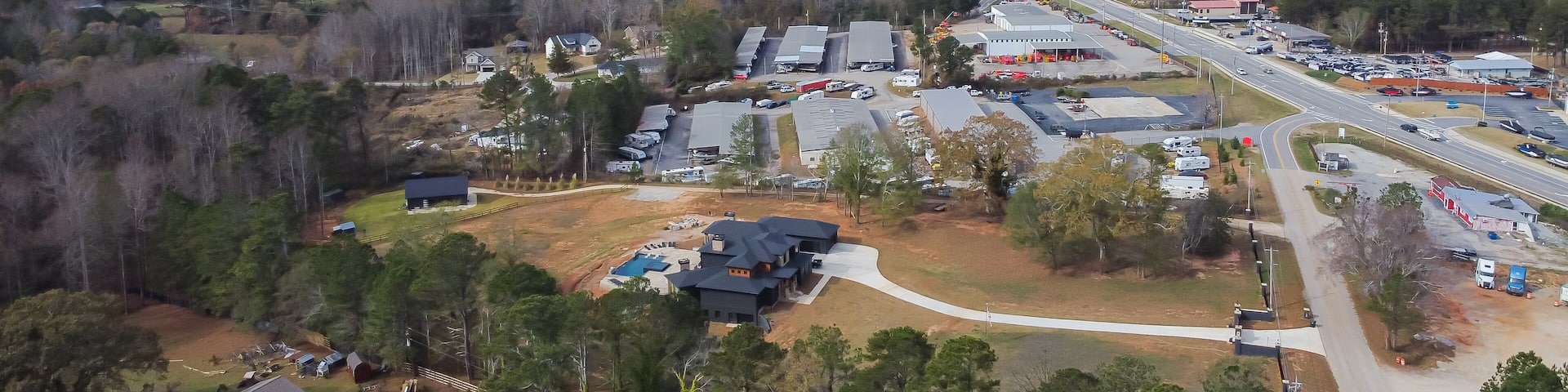 Aerial view Lanier Island Parkway with farm ranch style residential houses, commercial buildings and huge Lake Lanier in background cloud blue sky Buford, USA
