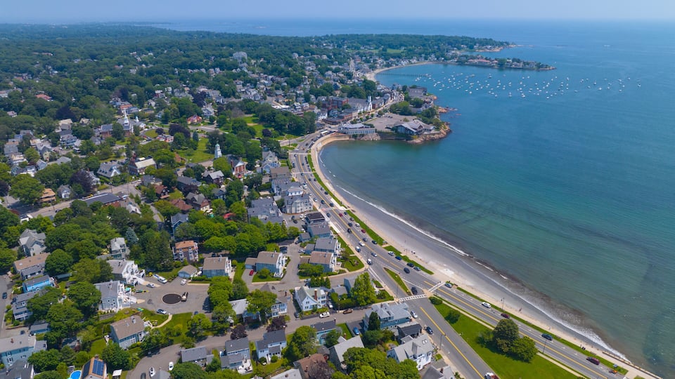 A coastal town with a curved beach, residential areas, and a clear view of the ocean.