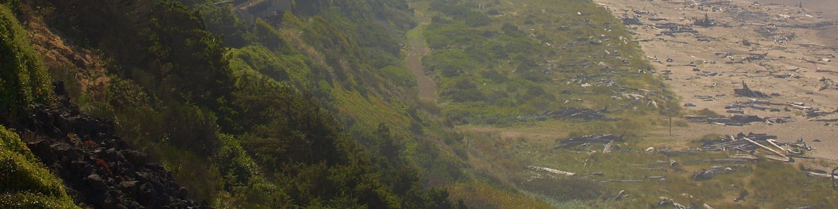 Eine Küstenlandschaft mit Strand, Klippen und Häusern an einem Hügelhang.