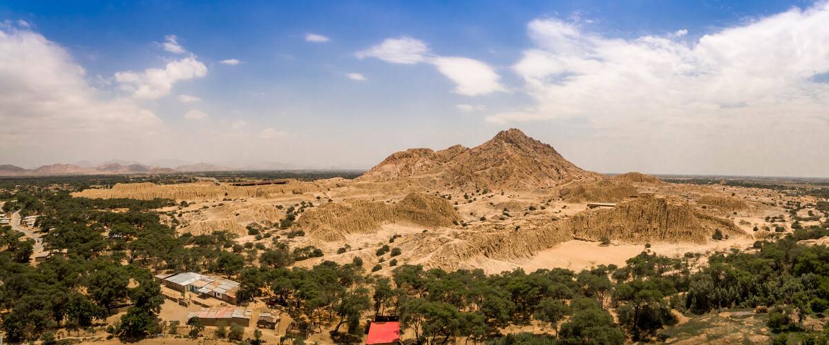 A rugged mountain range with sparse vegetation and a few scattered buildings.