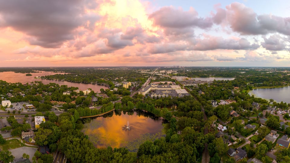A river winding through a town with a bridge, surrounded by greenery and buildings.