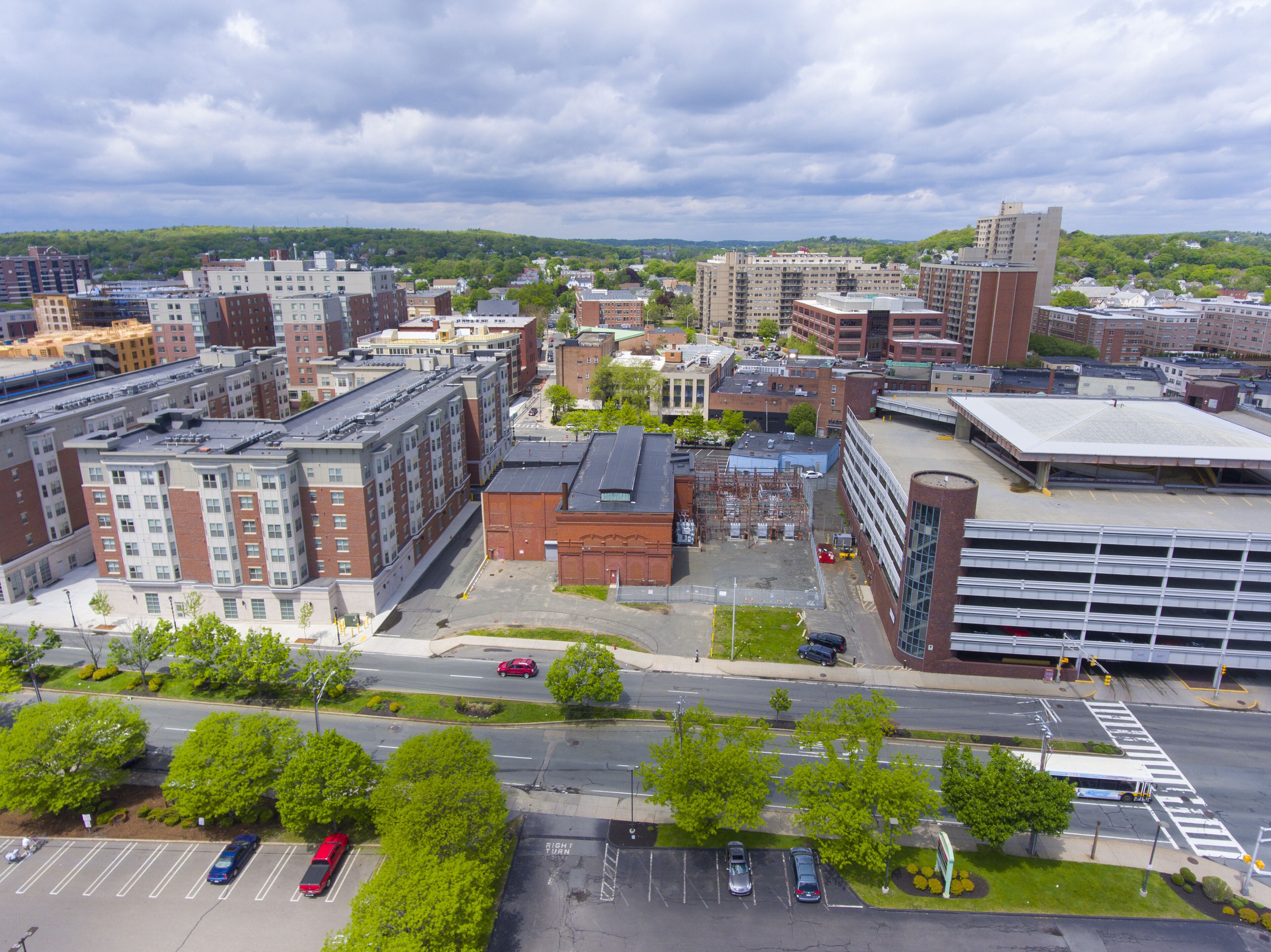 An urban landscape with multi-story buildings, a parking lot, and a road intersection.