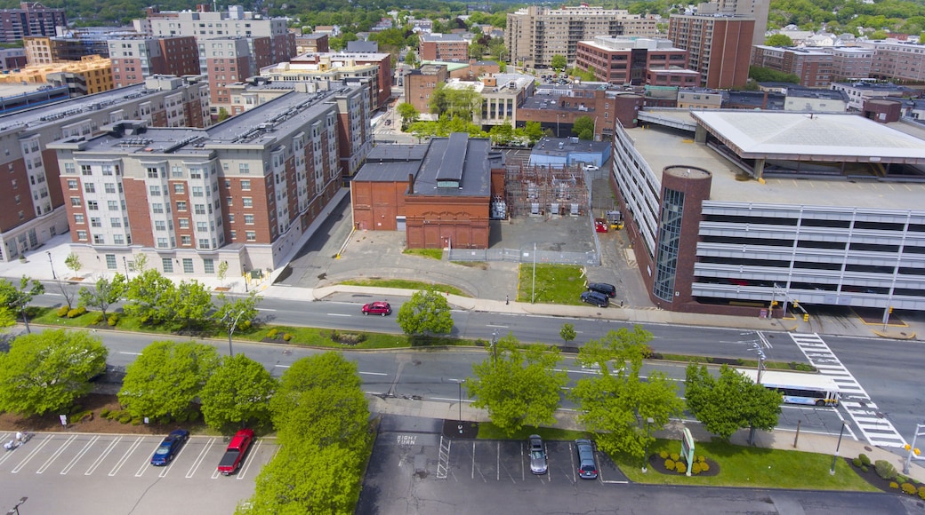 An urban landscape with multi-story buildings, a parking lot, and a road intersection.