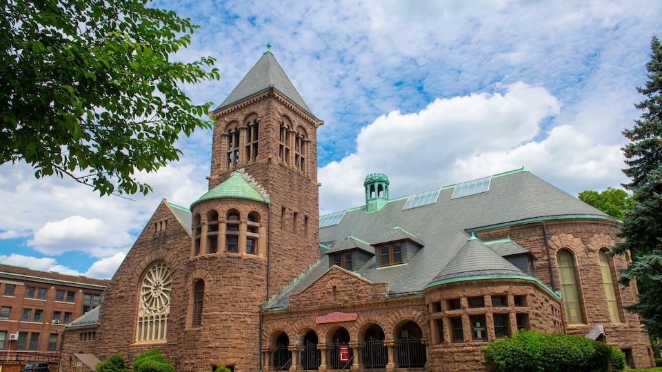 A historic church with a prominent tower, large arched windows, and a green roof.