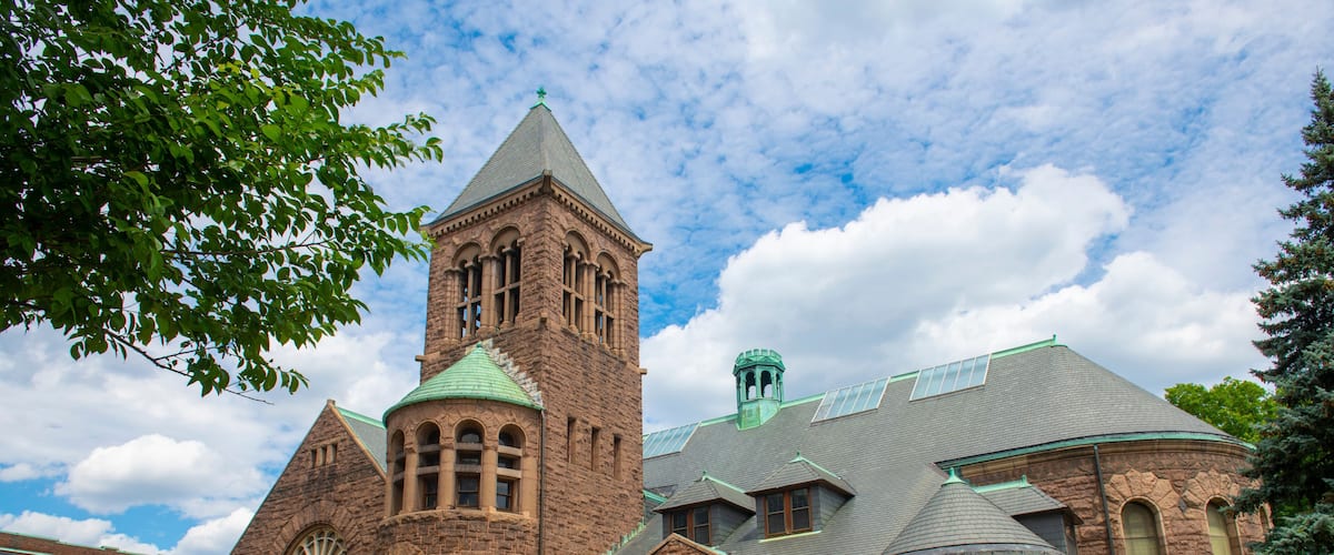 A historic church with a prominent tower, large arched windows, and a green roof.