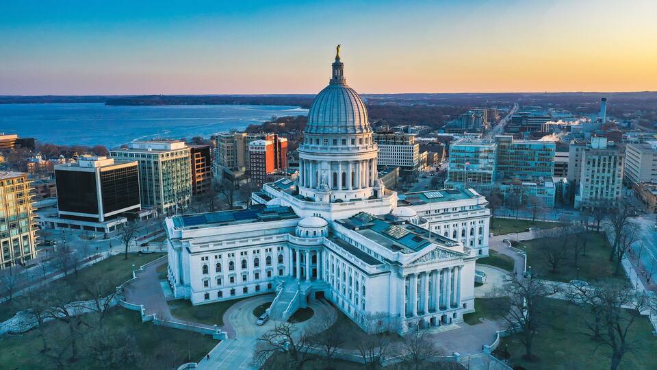 A large domed building surrounded by modern buildings and a river.