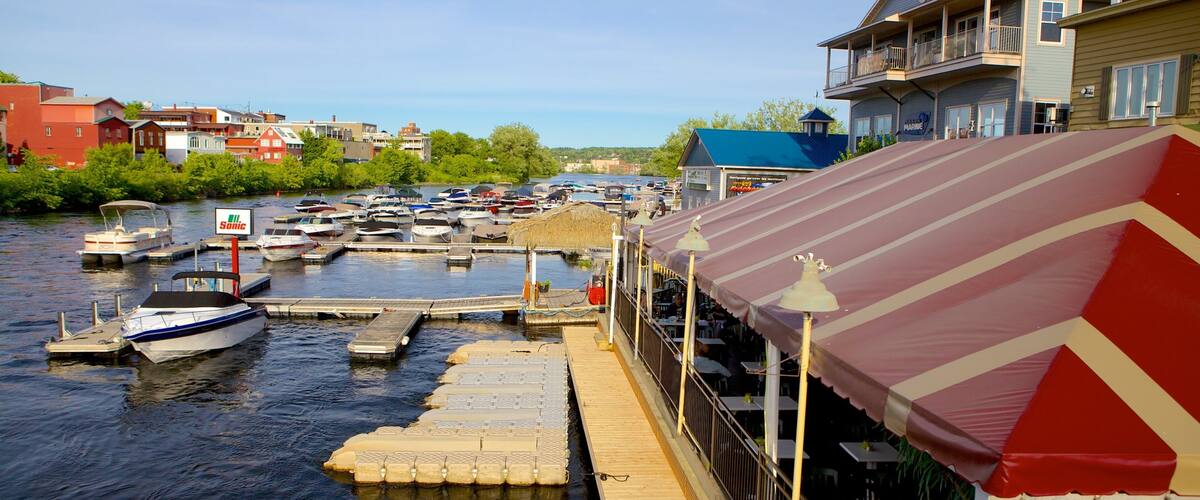 A marina with boats docked, a wooden dock, and a restaurant with a striped awning.