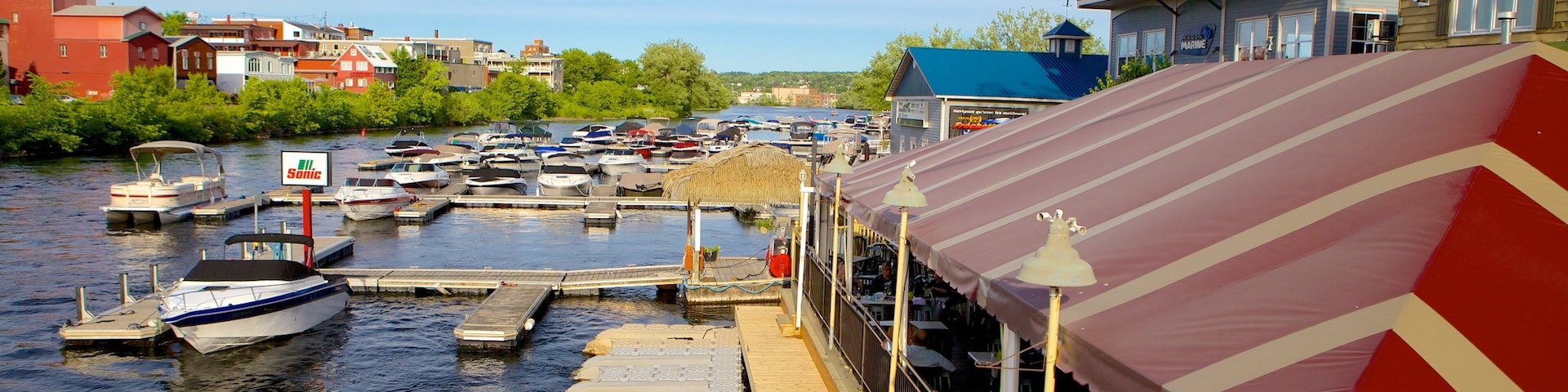 A marina with boats docked, a wooden dock, and a restaurant with a striped awning.