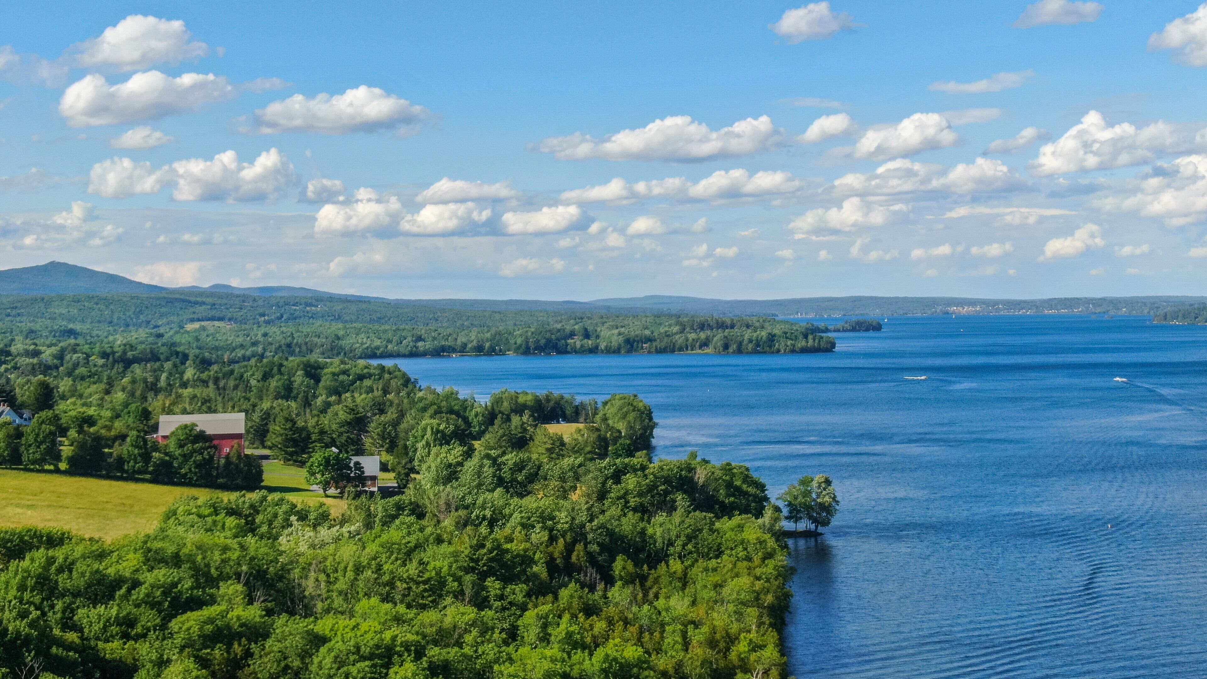 A lake surrounded by dense forests and a few houses.