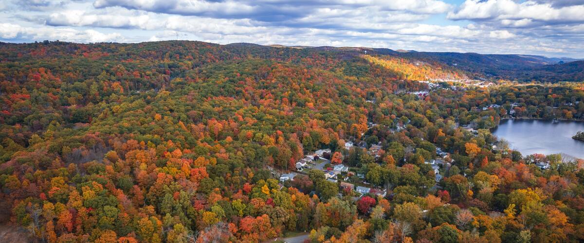 A mountainous landscape with autumn foliage, a lake, and a residential area.