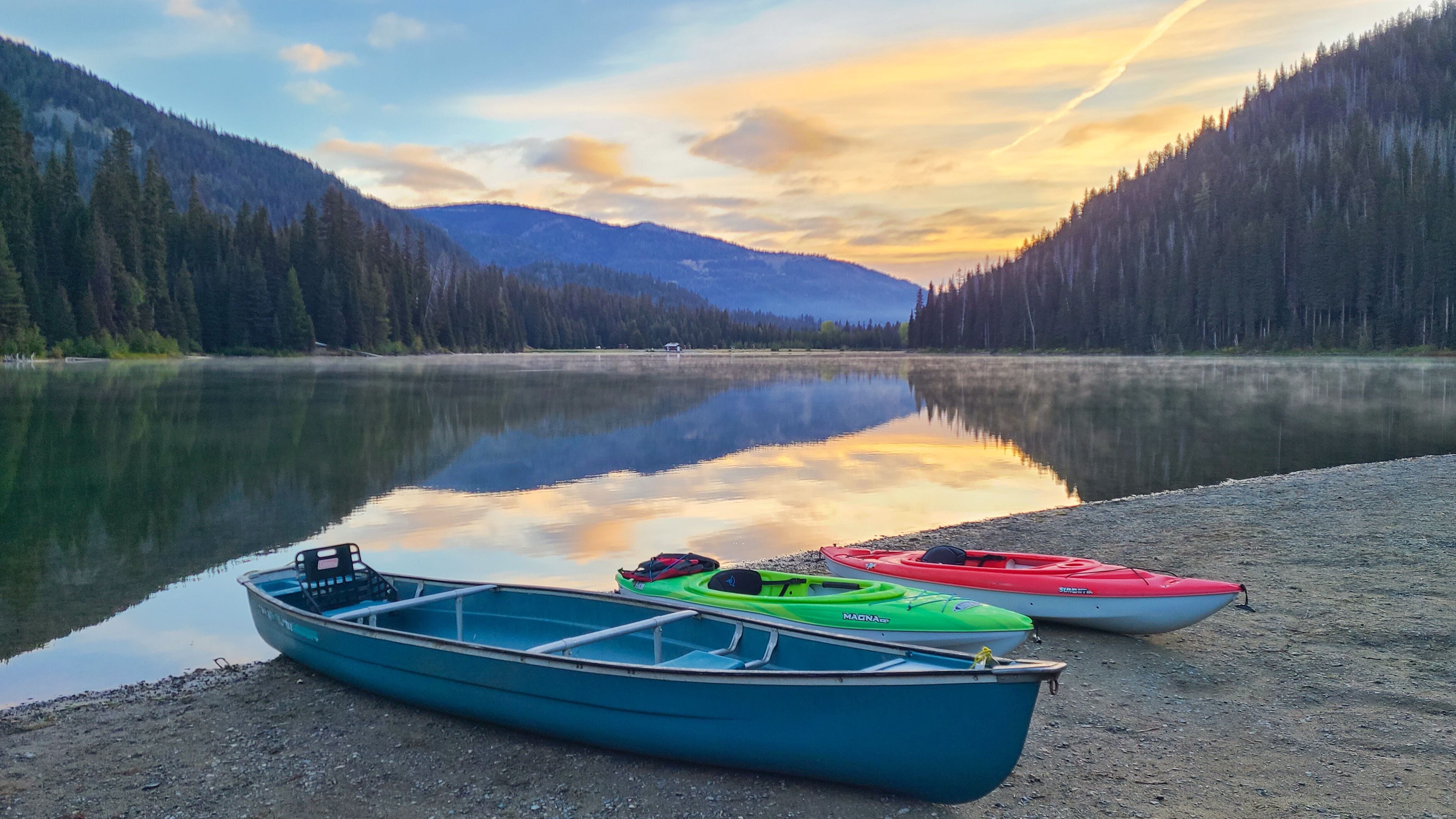 Peaceful morning at Lightning Lake with canoes on the shore and mountain reflections, Manning Park, Canada
