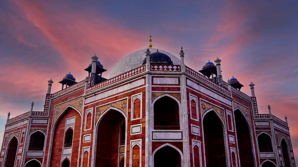 A large, ornate building with domes and arches, set against a colorful sky.