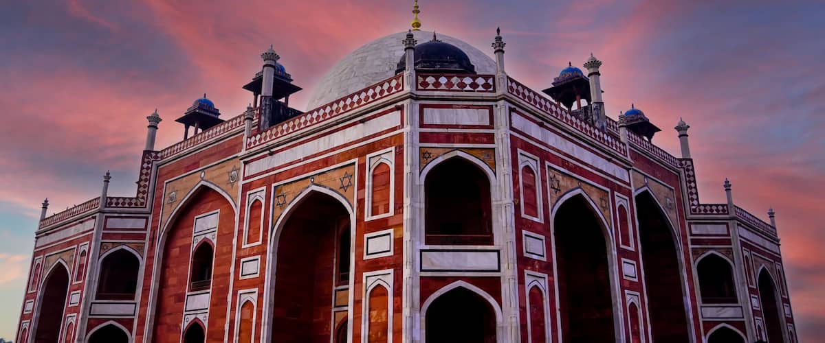 A large, ornate building with domes and arches, set against a colorful sky.