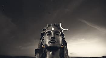 A statue with a crescent moon on its head, set against a twilight sky.