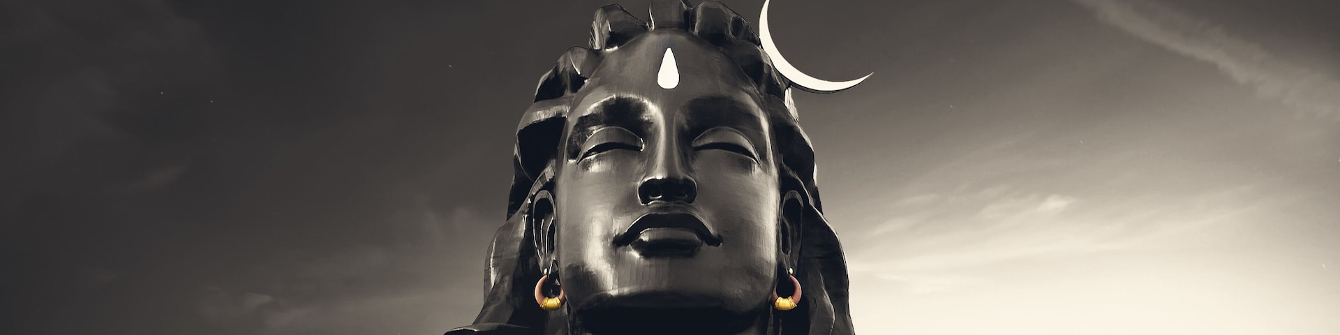 A statue with a crescent moon on its head, set against a twilight sky.