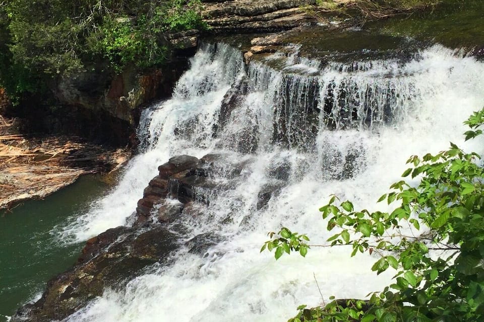 A waterfall cascading over rocky terrain surrounded by lush greenery.