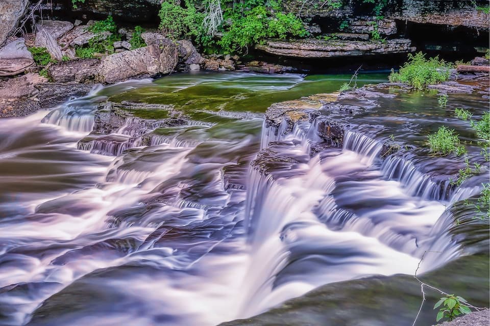A waterfall cascading over rocks in a forested area.