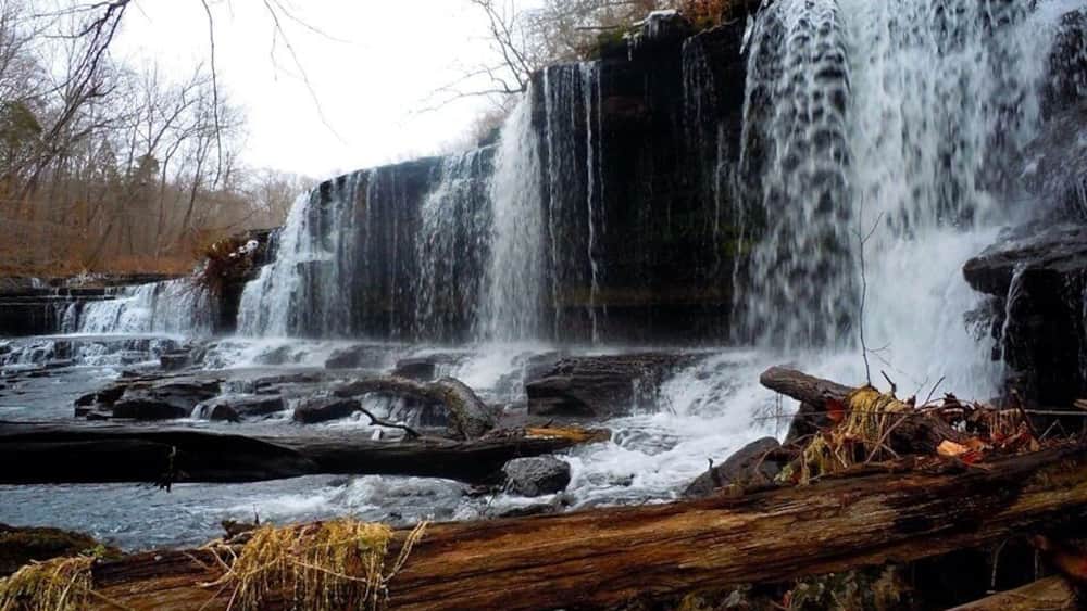 A waterfall cascading over rocks in a forested area.