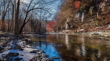 A winter stream in a mountain forest with sunlight, ice and snow. The Duck River in Old Stone Fort State Archaeological Park Manchester Tennessee USA.