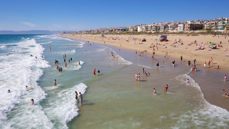 A crowded beach with waves crashing onto the shore and people enjoying the water.