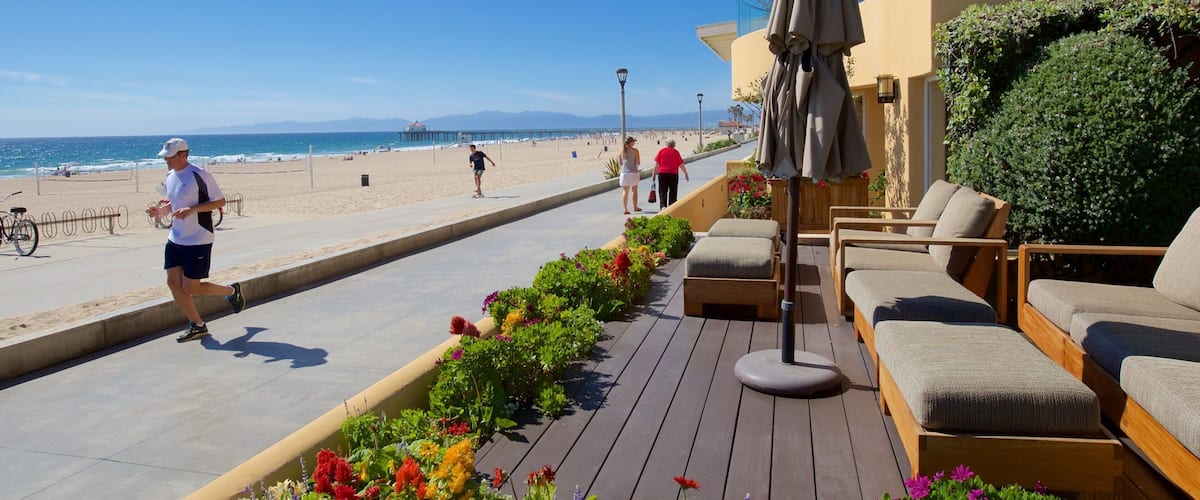 A beach promenade with a wooden deck, outdoor seating, and a view of the ocean.