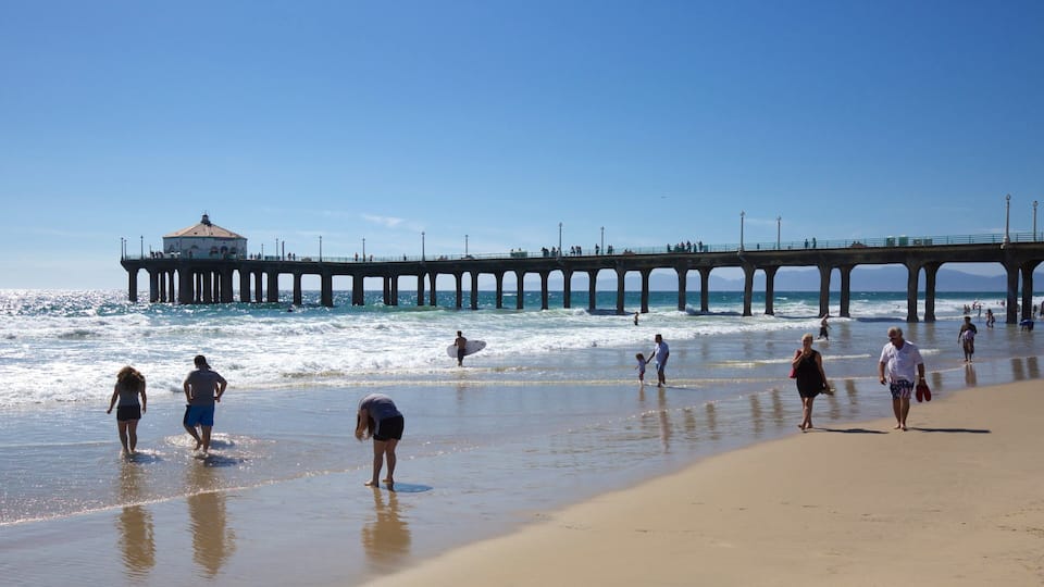 A pier extending into the ocean with people walking along the beach.