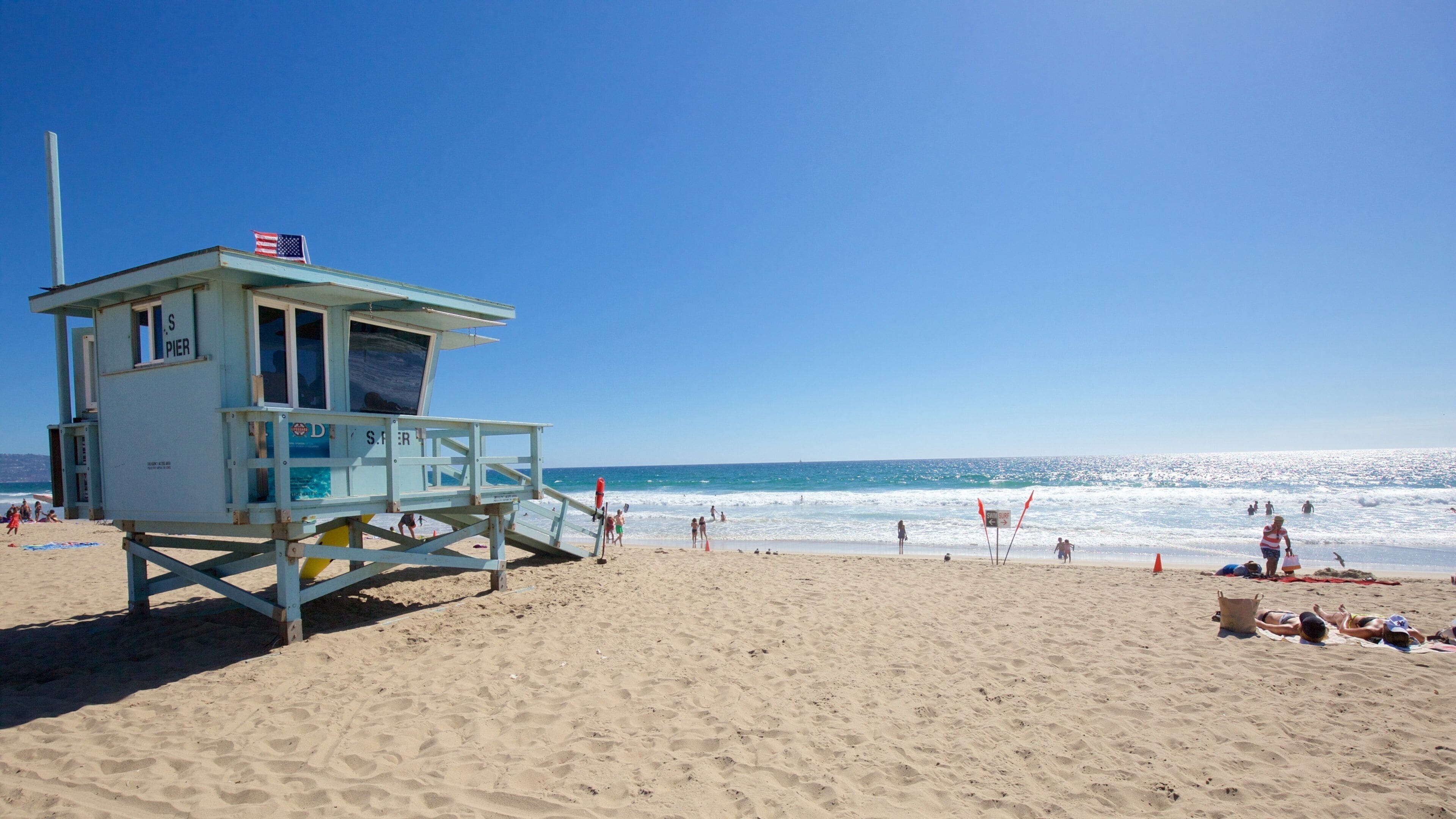 A lifeguard tower on a sandy beach with the ocean in the background.
