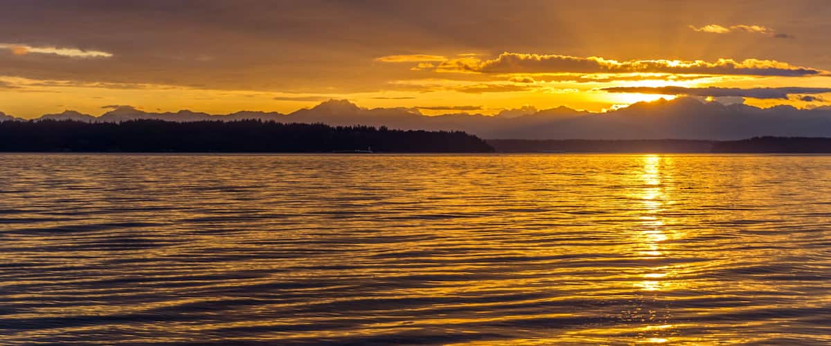 A sunset over a calm lake with mountains in the background.