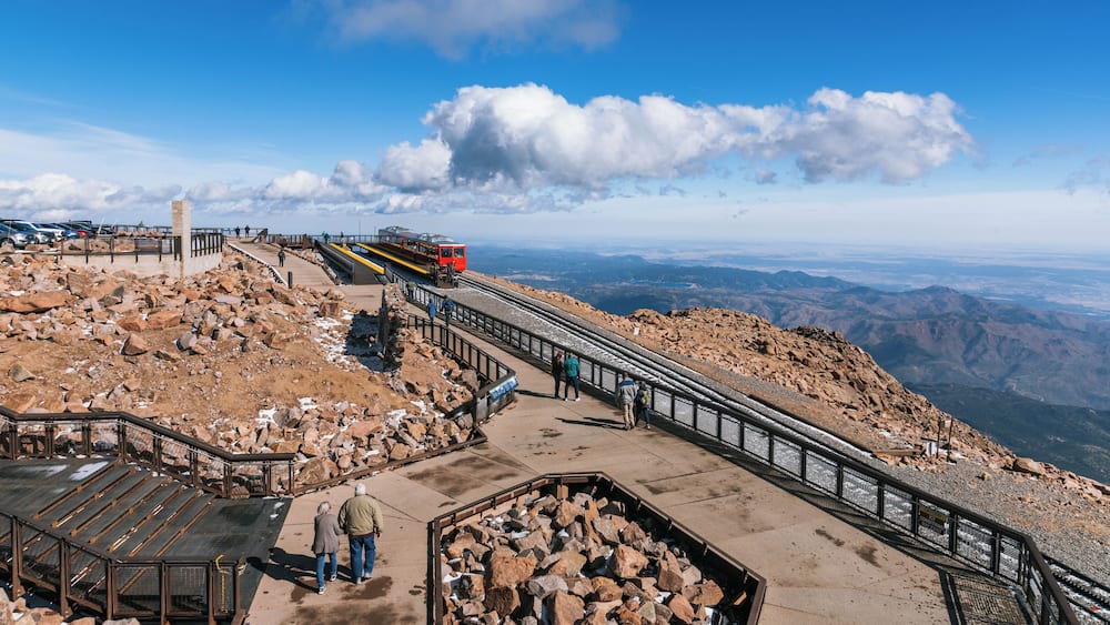 A mountain trail with a cable car system, rocky terrain, and a clear sky.