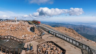 Trilha de montanha com sistema de teleférico, terreno rochoso e céu claro.