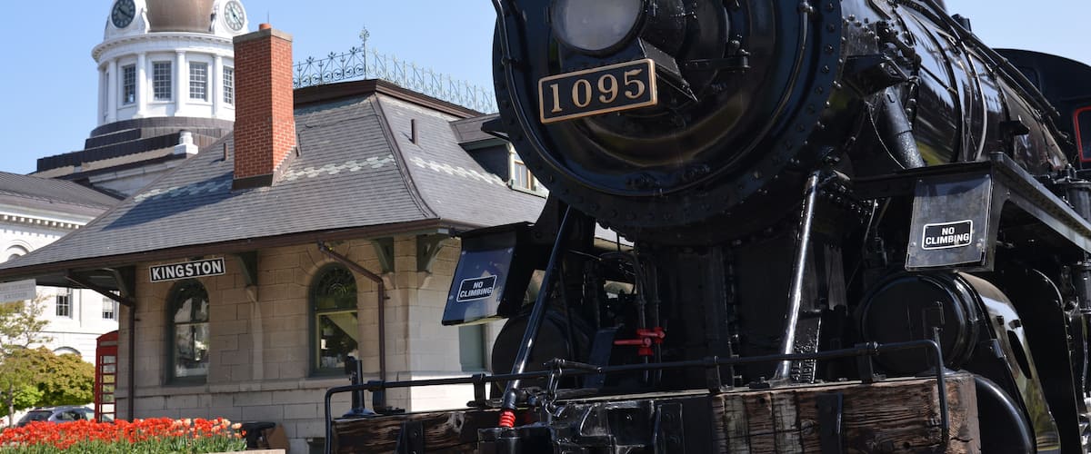 A steam locomotive numbered 1095 at a station with a dome and 'KINGSTON' sign.