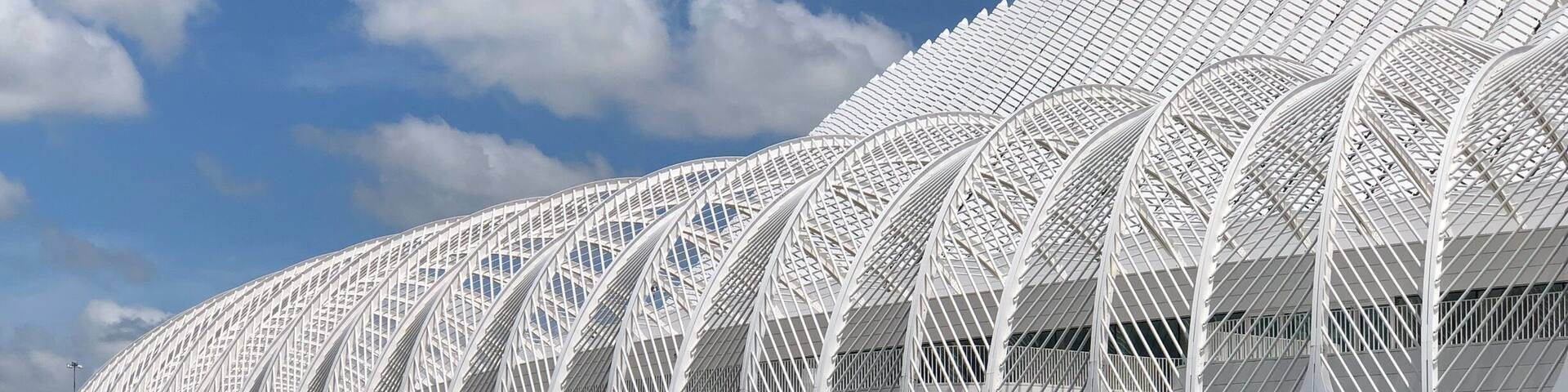 A modern white architectural structure with a reflective surface, situated beside a body of water.