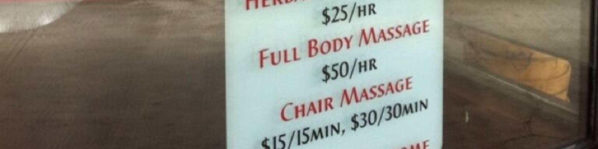 Une vitrine avec une enseigne au néon indiquant un service de massage des pieds et un panneau affichant les prix des différents types de massages proposés.