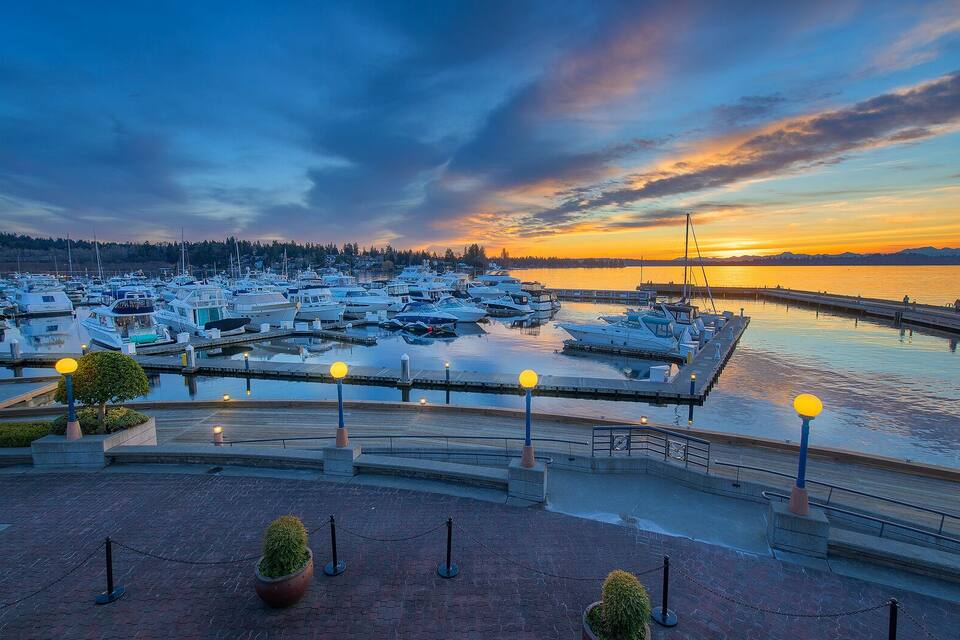 A marina at sunset with boats docked, a pier, and a sunset over the water.