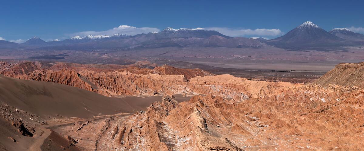 A vast desert landscape with rugged mountains in the background.