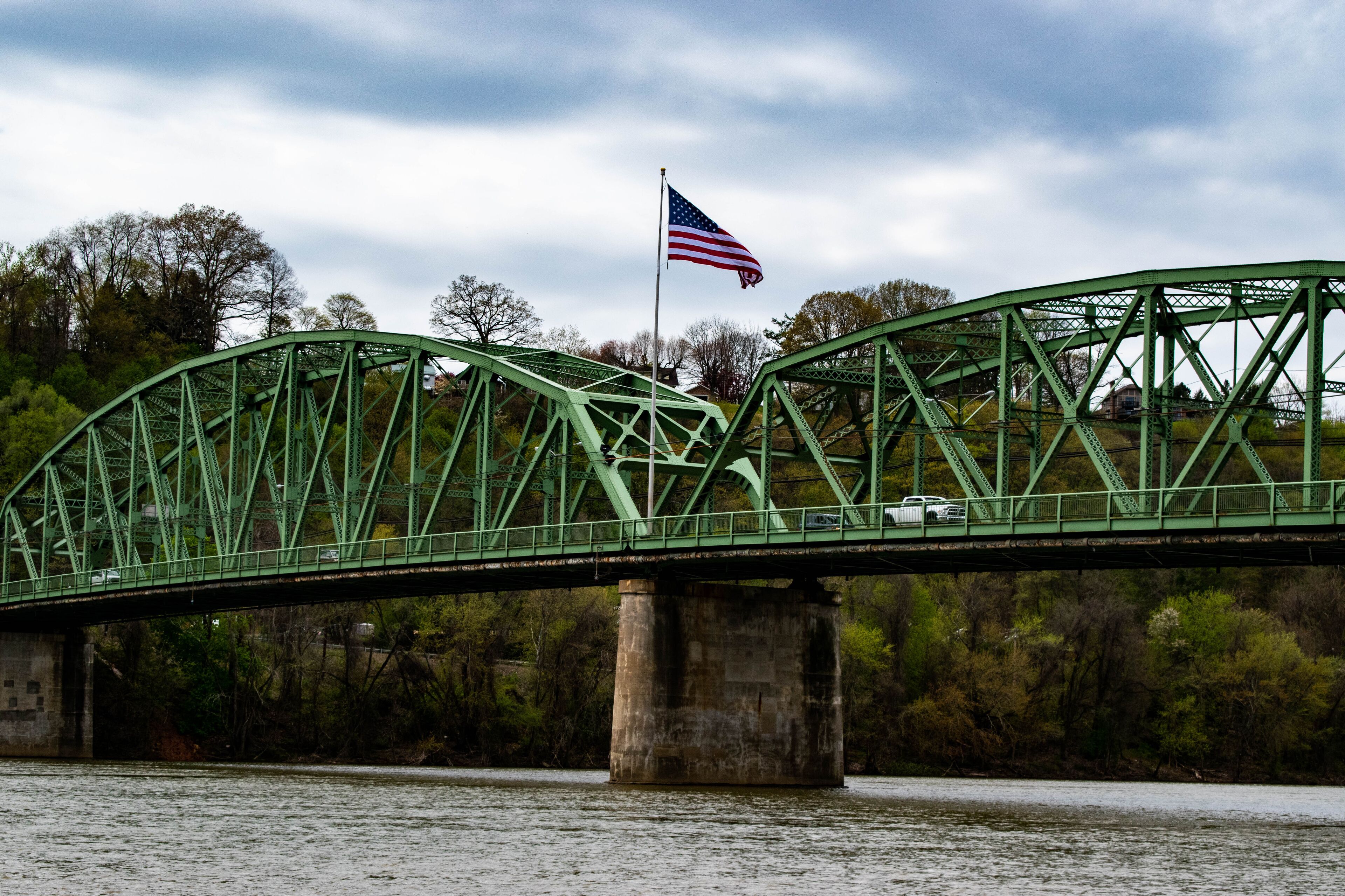 A green metal bridge with an American flag.