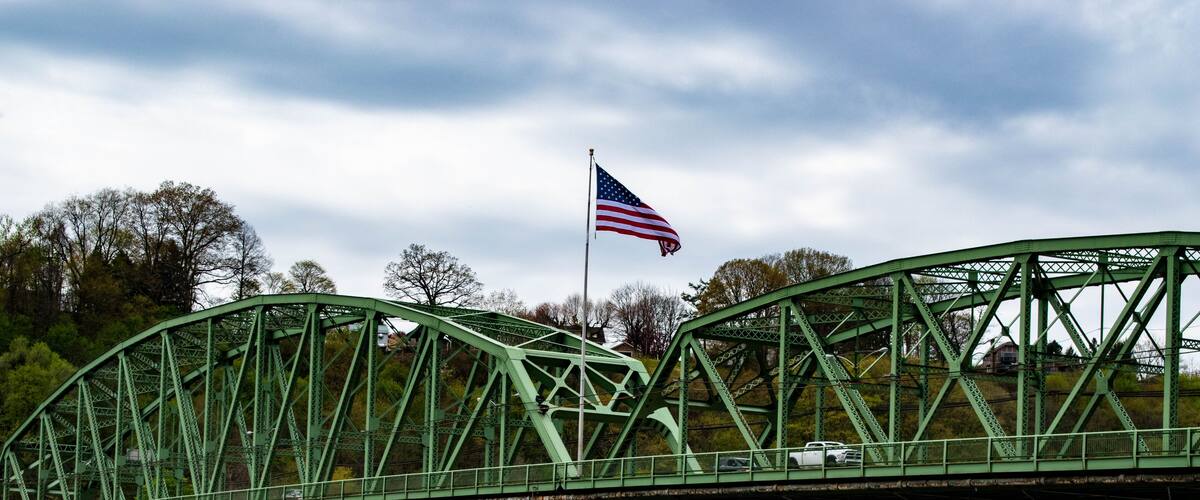A green metal bridge with an American flag.