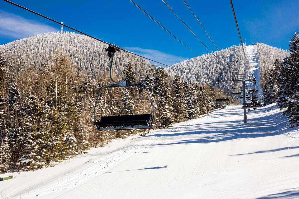 A ski lift with a chairlift ascending a snowy mountain slope.