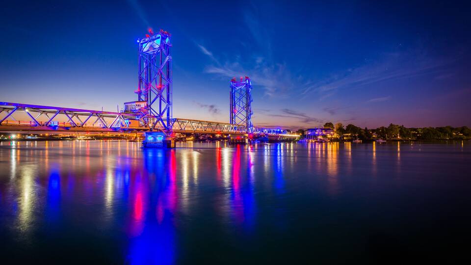 A bridge with illuminated structures at dusk.