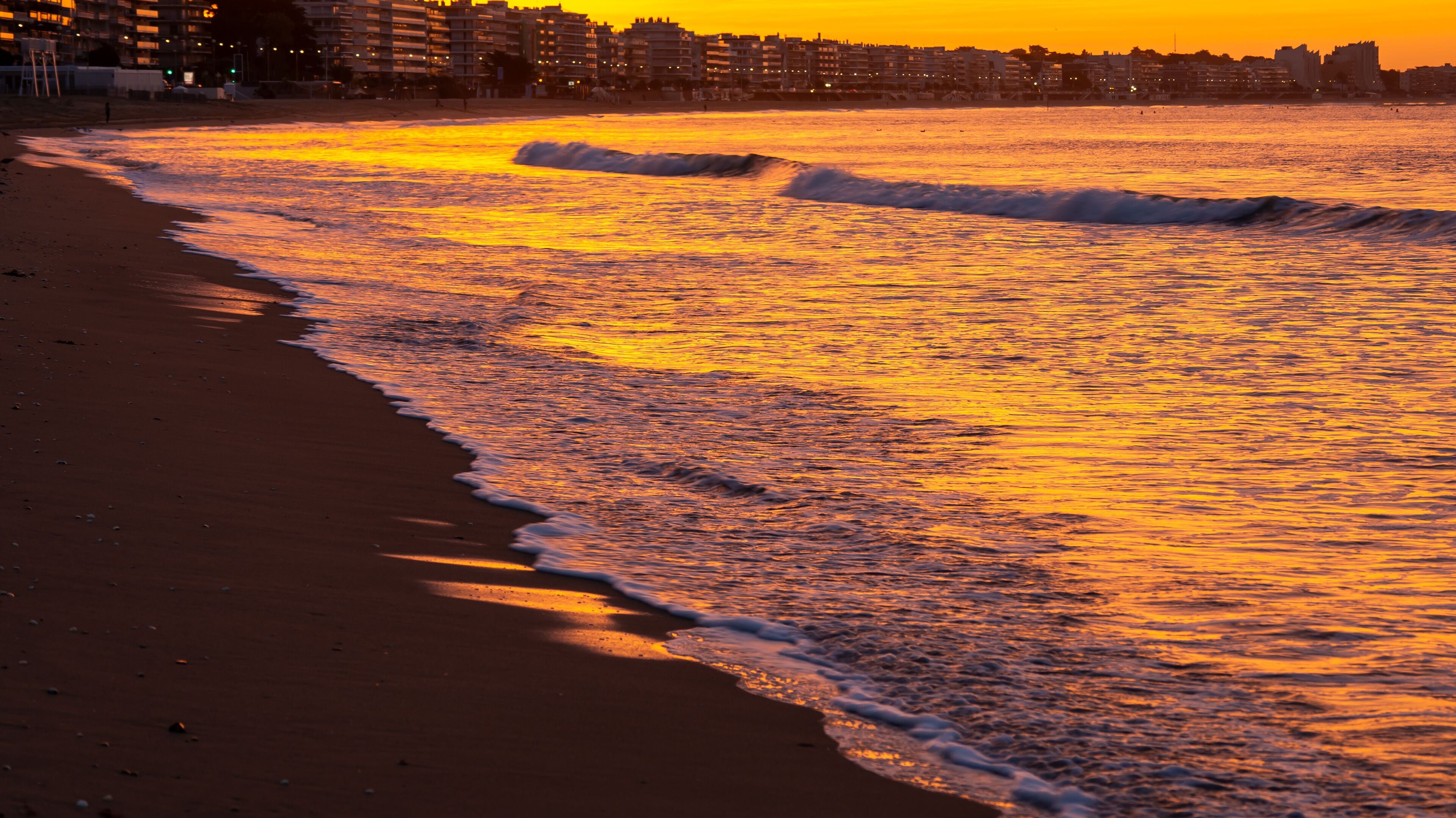 Amazing view of a fiery sunrise with multicolored clouds. Sea waves along the seashore at sunrise. Morning time. Ocean view. La Baule-Escoublac, France
