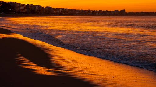 Amazing view of a fiery sunrise with multicolored clouds. Sea waves along the seashore at sunrise. Morning time. Ocean view. La Baule-Escoublac, France