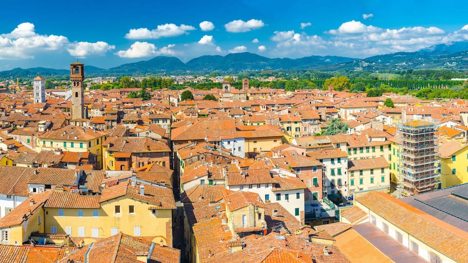 A densely packed town with red-tiled roofs, historic buildings, and a prominent church tower.