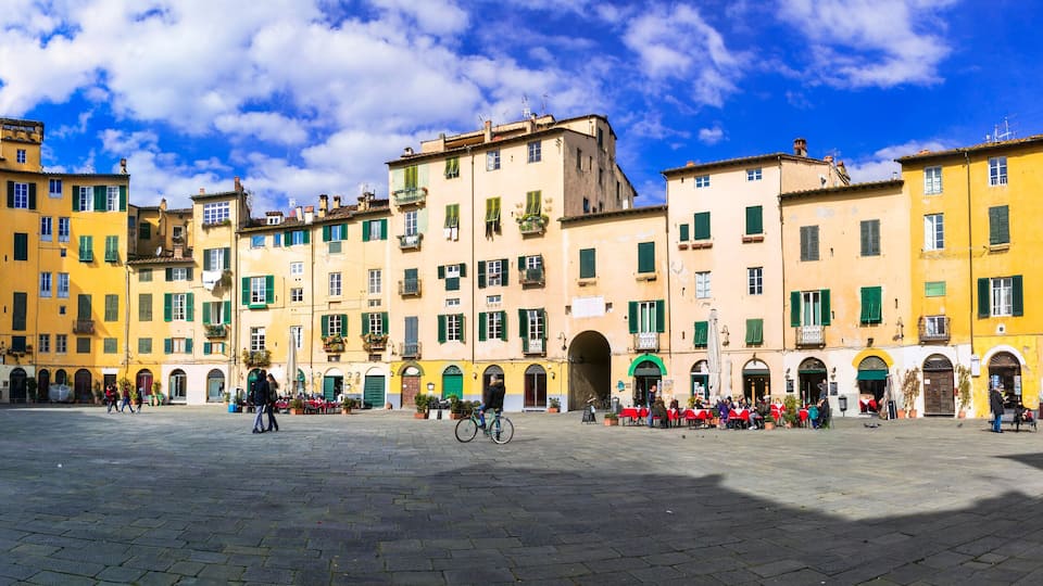 A historic square with colorful buildings, cobblestone pavement, and outdoor seating areas.