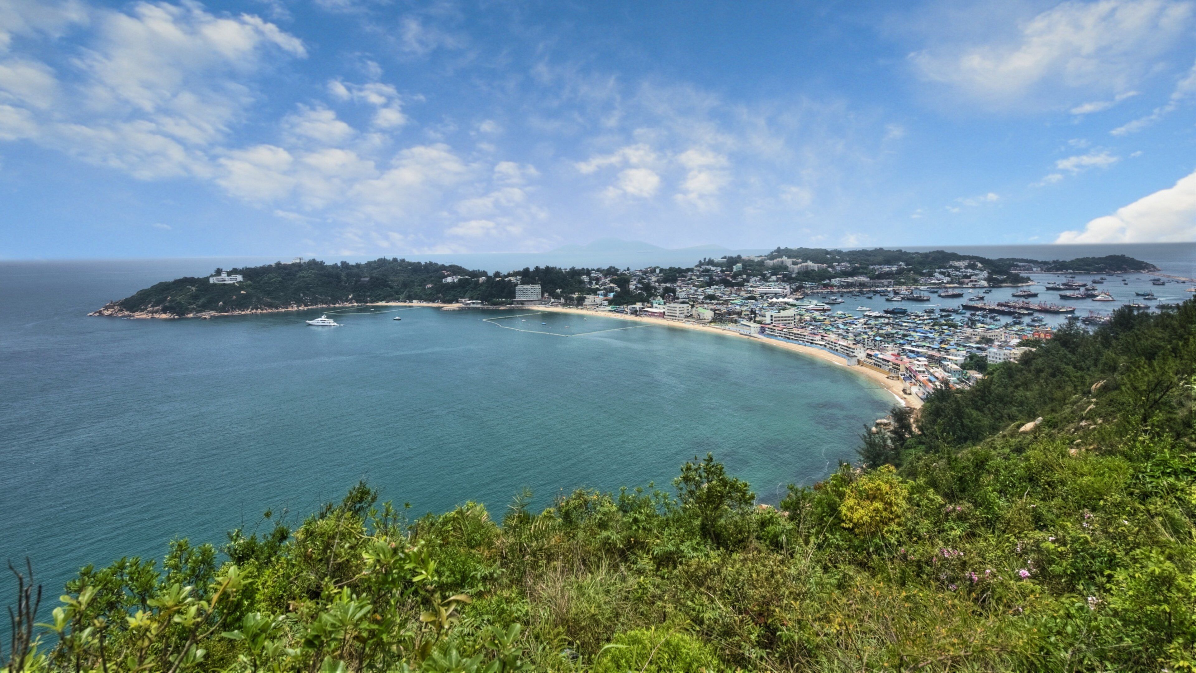 A coastal town with a bay, boats, and a beach.
