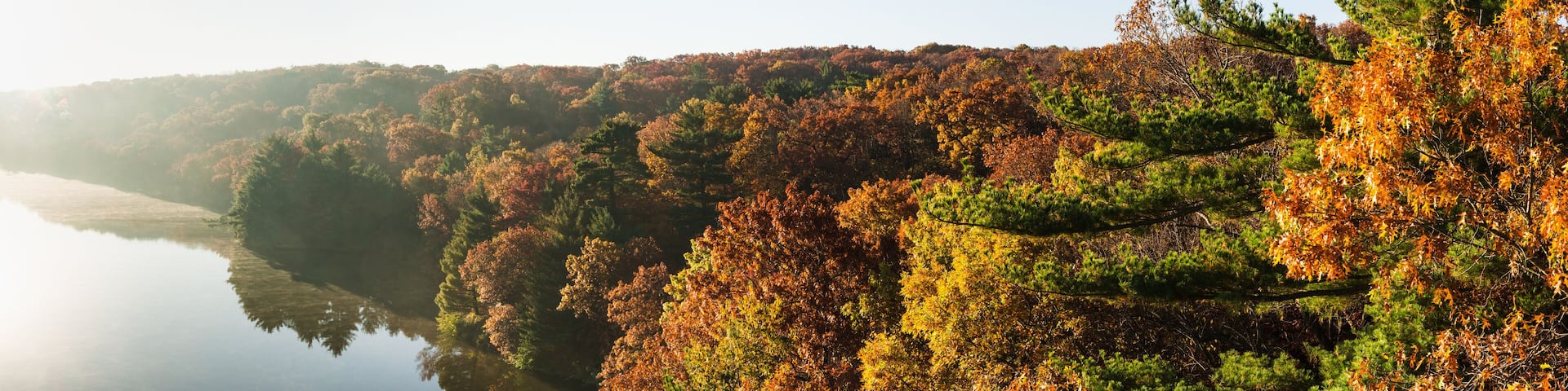 Autumn colors on the Illinois River as the morning sun lights up the tree tops. Starved Rock State Park, Illinois, USA