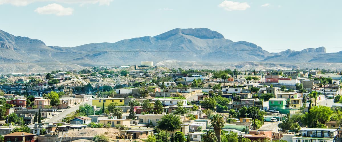 A town with colorful buildings, a mountain in the background, and a clear sky.
