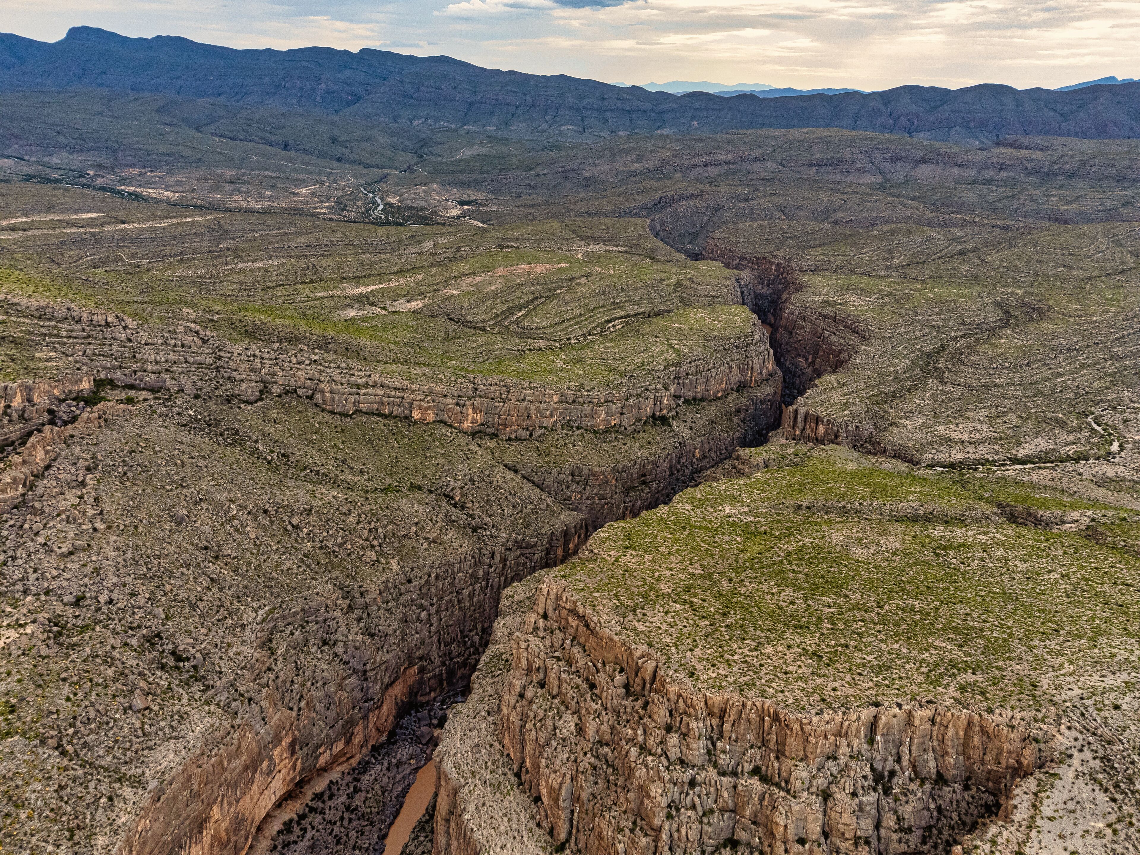 Un cañón con formaciones rocosas estratificadas y un río que lo atraviesa.