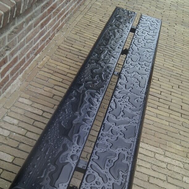 In between this fake buildings, the waterpatterns on an iron bench suddenly are of utmost beauty
